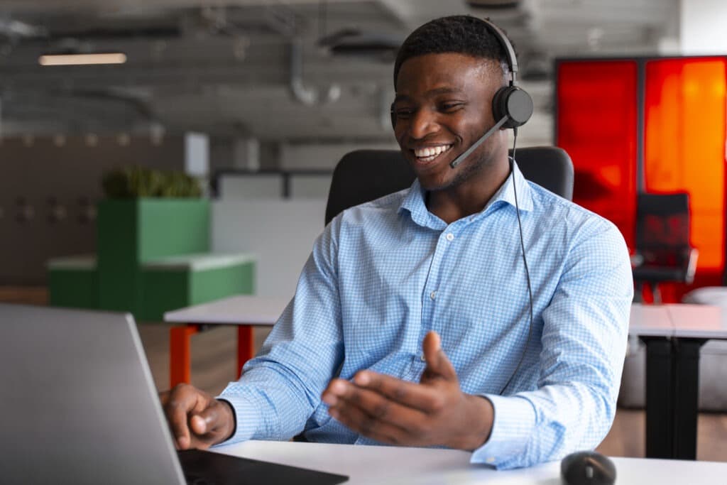 Customer service agent using VoIP headset while working on computer in modern office